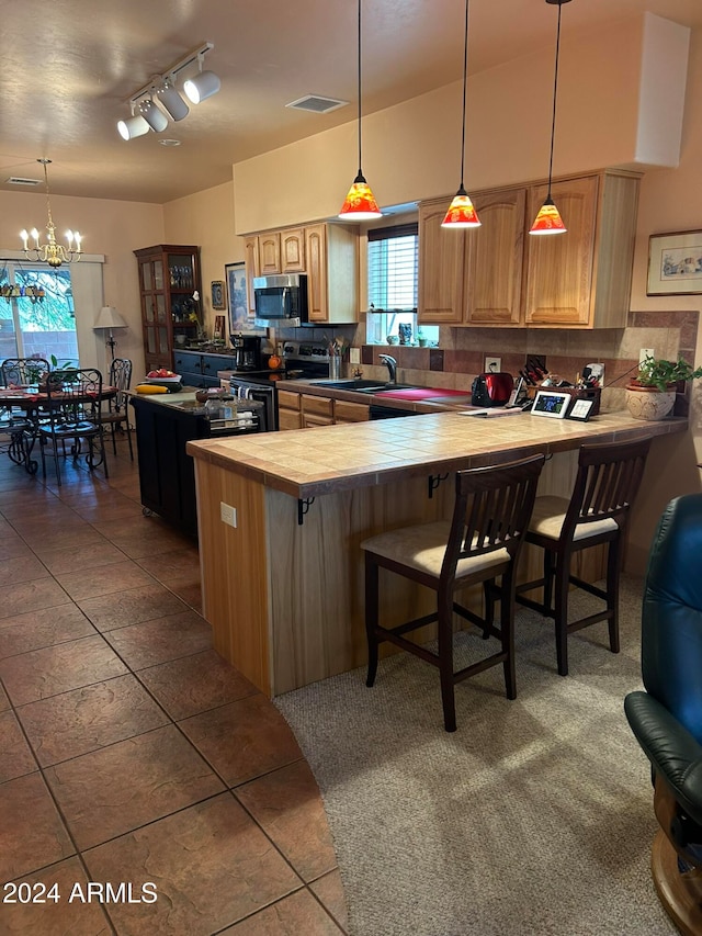 kitchen featuring kitchen peninsula, backsplash, a breakfast bar area, and appliances with stainless steel finishes