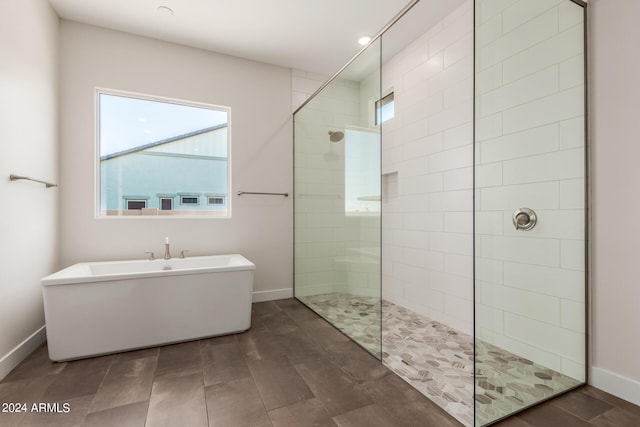 bathroom featuring a freestanding bath, walk in shower, and baseboards