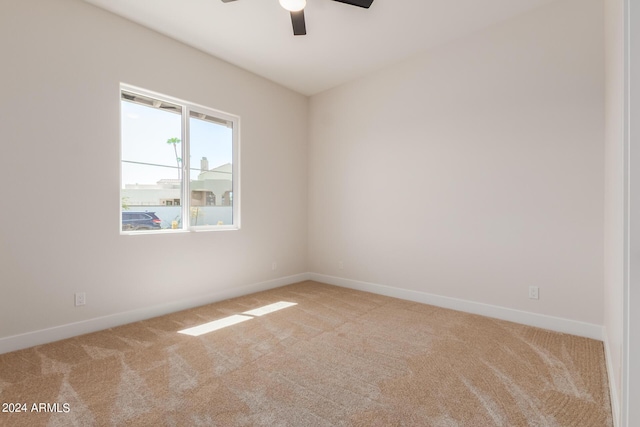 empty room with baseboards, a ceiling fan, and light colored carpet