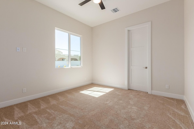 spare room featuring a ceiling fan, light colored carpet, visible vents, and baseboards