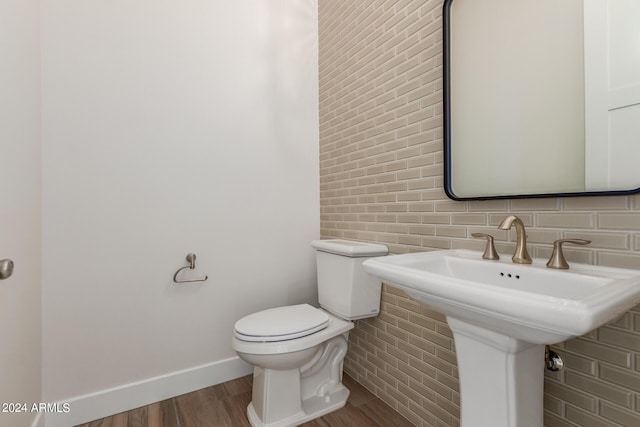 half bath featuring toilet, baseboards, and wood finished floors