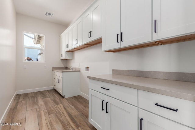 kitchen featuring visible vents, white cabinets, baseboards, light countertops, and light wood-type flooring