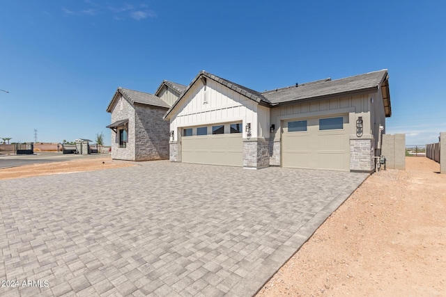 view of front facade featuring board and batten siding, decorative driveway, and an attached garage