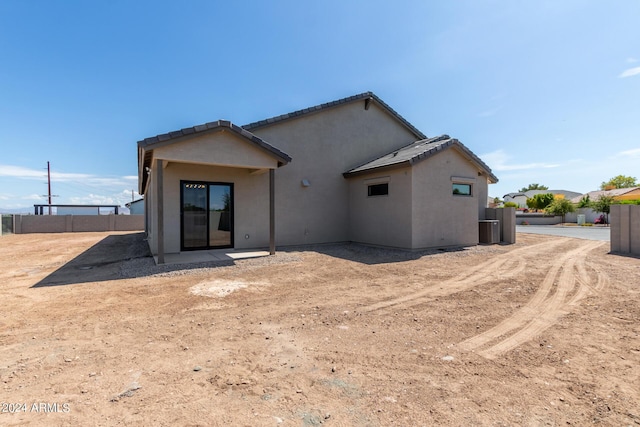 back of house featuring a tile roof, fence, and stucco siding