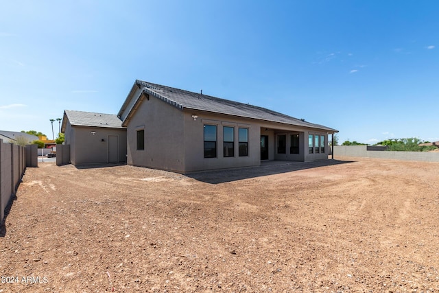 rear view of house featuring a fenced backyard and stucco siding