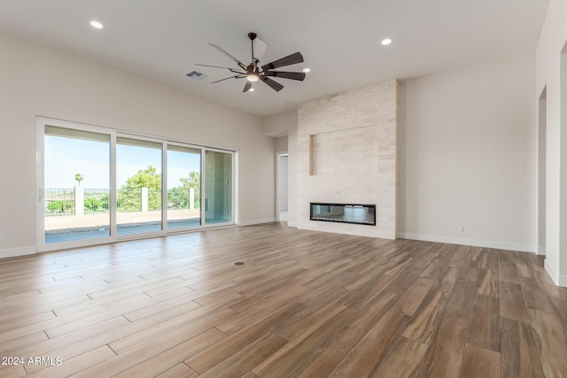 unfurnished living room with a large fireplace, visible vents, ceiling fan, wood finished floors, and recessed lighting