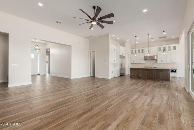 unfurnished living room featuring light wood finished floors, visible vents, ceiling fan, a sink, and recessed lighting