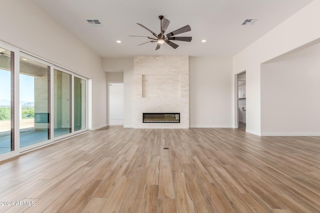 unfurnished living room with light wood-type flooring, a fireplace, visible vents, and baseboards