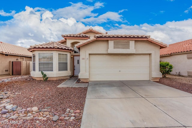 mediterranean / spanish-style house featuring concrete driveway, a tiled roof, an attached garage, and stucco siding