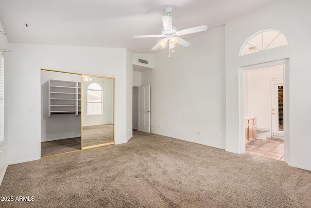 unfurnished bedroom featuring visible vents, high vaulted ceiling, ensuite bath, a closet, and carpet flooring