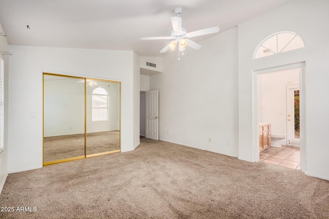 unfurnished bedroom with visible vents, carpet, ensuite bathroom, a closet, and high vaulted ceiling