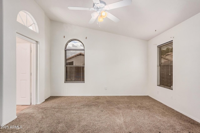 unfurnished room with vaulted ceiling, a healthy amount of sunlight, carpet, and ceiling fan
