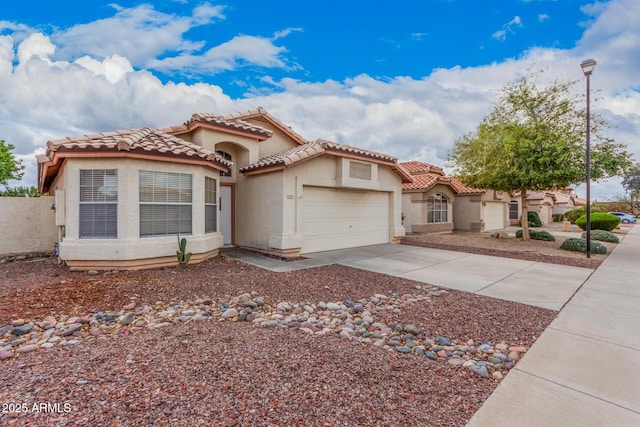 mediterranean / spanish home featuring stucco siding, a tiled roof, an attached garage, and concrete driveway