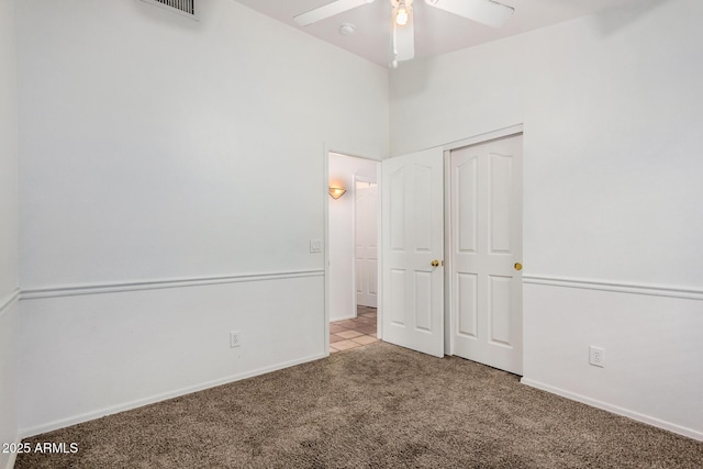 unfurnished bedroom featuring a closet, carpet floors, baseboards, and a ceiling fan