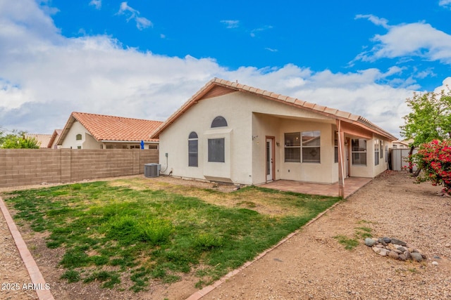 back of house with stucco siding, central air condition unit, a patio, a fenced backyard, and a yard