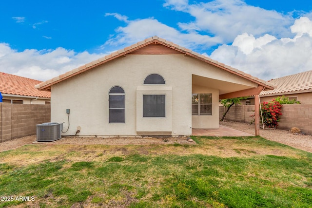 rear view of house featuring a fenced backyard, stucco siding, a tile roof, a patio area, and a lawn