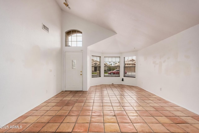 foyer entrance with light tile patterned floors, visible vents, and high vaulted ceiling