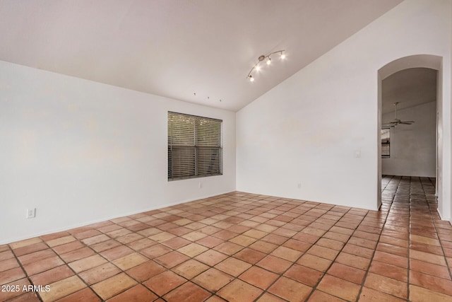 empty room with light tile patterned floors, arched walkways, and vaulted ceiling