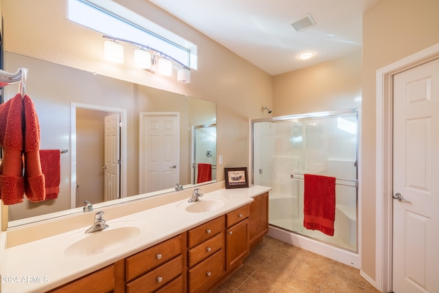 bathroom featuring dual sinks, tile flooring, an enclosed shower, and vanity with extensive cabinet space