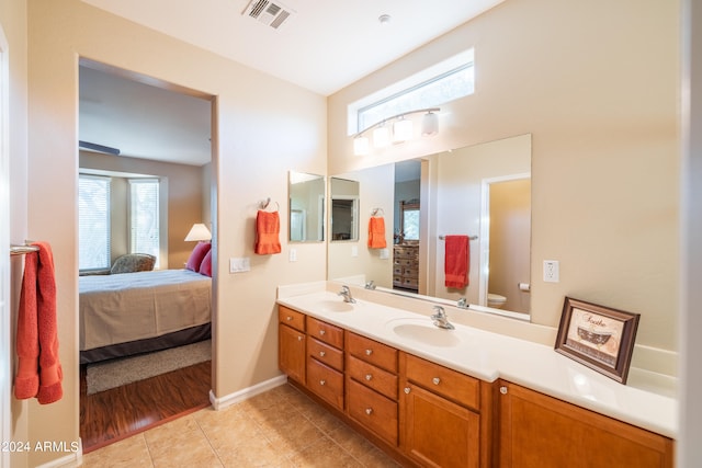 bathroom featuring toilet, double sink, vanity with extensive cabinet space, and tile flooring