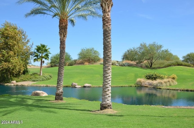 surrounding community with a water view and a lawn