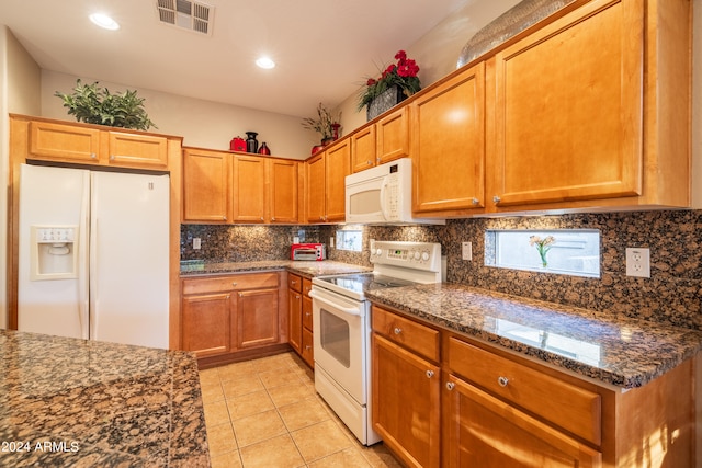 kitchen featuring backsplash, white appliances, dark stone countertops, and light tile flooring