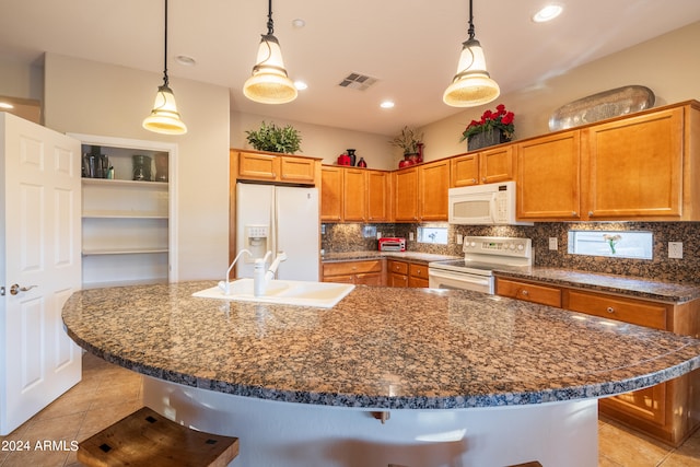 kitchen with a breakfast bar, pendant lighting, white appliances, and sink