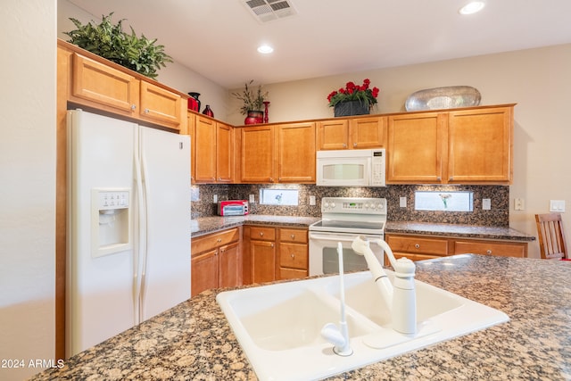 kitchen featuring sink, white appliances, backsplash, and dark stone countertops