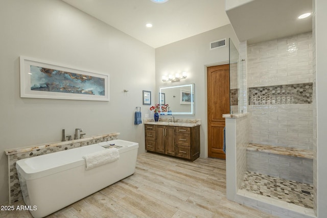 bathroom featuring hardwood / wood-style flooring, vanity, and separate shower and tub