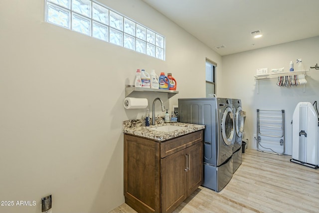 washroom with independent washer and dryer, sink, and light hardwood / wood-style flooring