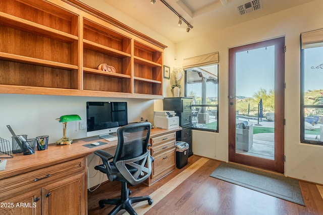 office featuring light hardwood / wood-style flooring, built in desk, and track lighting