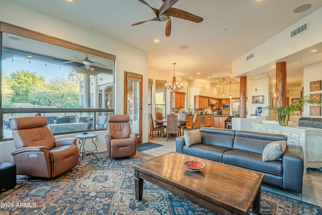 living room with ceiling fan with notable chandelier and plenty of natural light