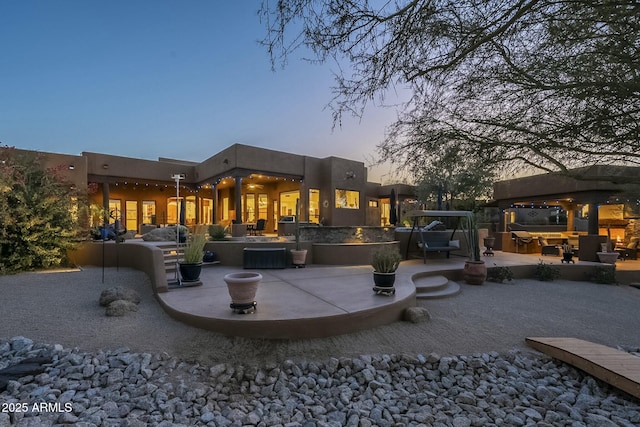 back house at dusk featuring a patio