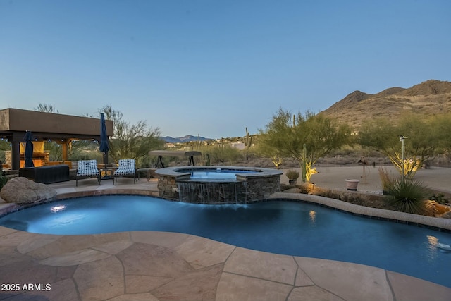 view of swimming pool featuring a patio, a mountain view, pool water feature, and an in ground hot tub