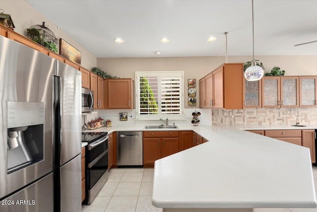 kitchen featuring appliances with stainless steel finishes, sink, kitchen peninsula, decorative light fixtures, and light tile patterned floors