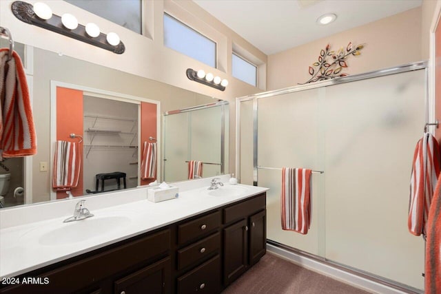 bathroom featuring a shower with door, vanity, and toilet