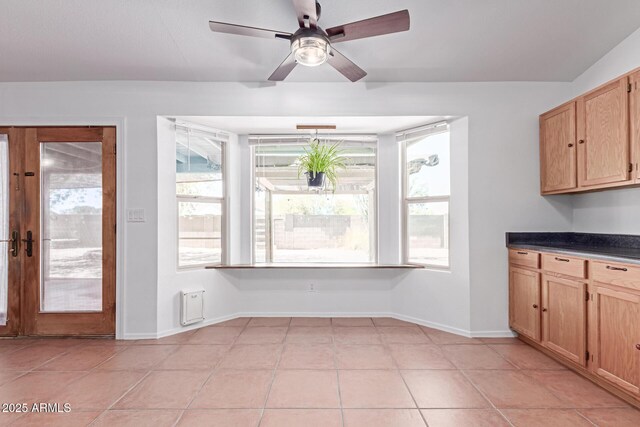 kitchen featuring dark countertops, light brown cabinets, baseboards, and ceiling fan