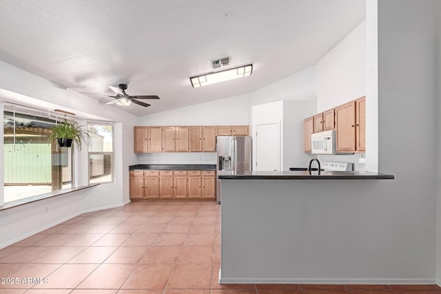 kitchen featuring a ceiling fan, dark countertops, stainless steel fridge, lofted ceiling, and white microwave