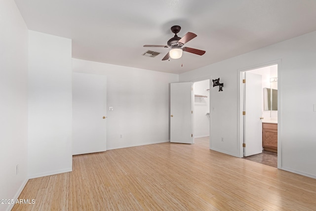 unfurnished bedroom featuring visible vents, baseboards, light wood-style floors, and a walk in closet