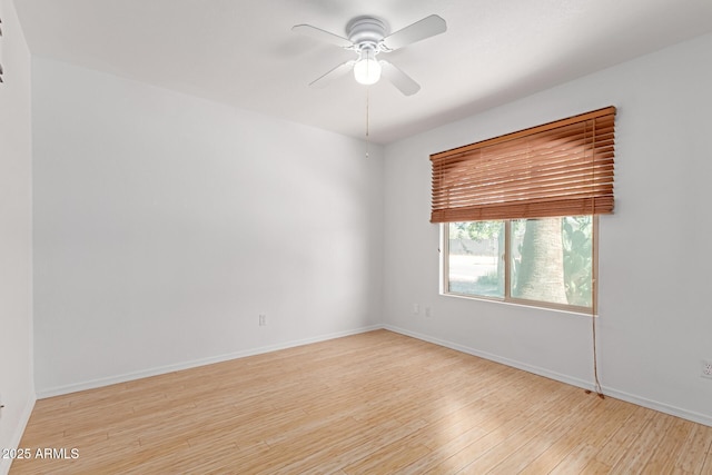 empty room with wood finished floors, a ceiling fan, and baseboards