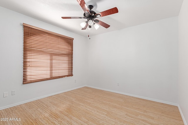 spare room featuring a ceiling fan, light wood-type flooring, and baseboards