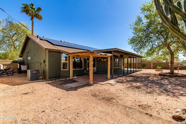 back of property with a patio, central AC unit, solar panels, a fenced backyard, and a shingled roof