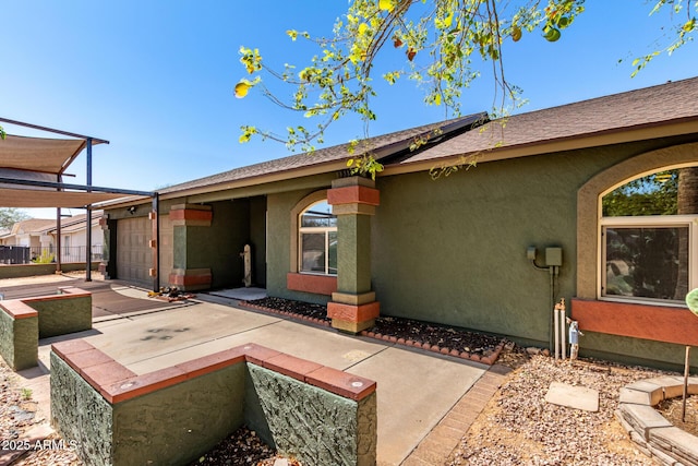 rear view of property with stucco siding and a garage