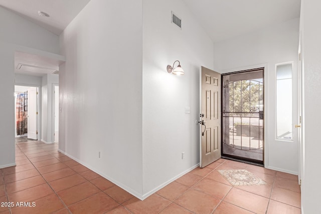 entrance foyer with light tile patterned floors, visible vents, and high vaulted ceiling