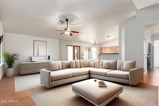 living room featuring visible vents, light wood-style floors, a ceiling fan, and vaulted ceiling