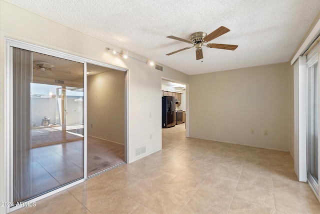 empty room with ceiling fan, light tile patterned floors, a textured ceiling, and a wealth of natural light