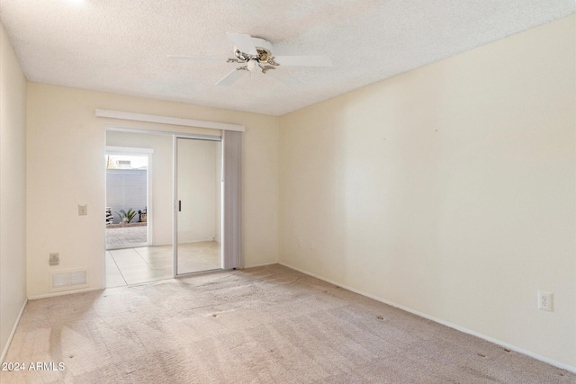 spare room with a textured ceiling, ceiling fan, and light carpet