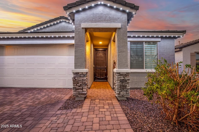 exterior entry at dusk featuring a garage