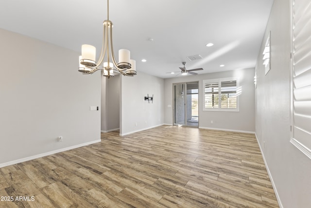spare room featuring ceiling fan with notable chandelier and light wood-type flooring