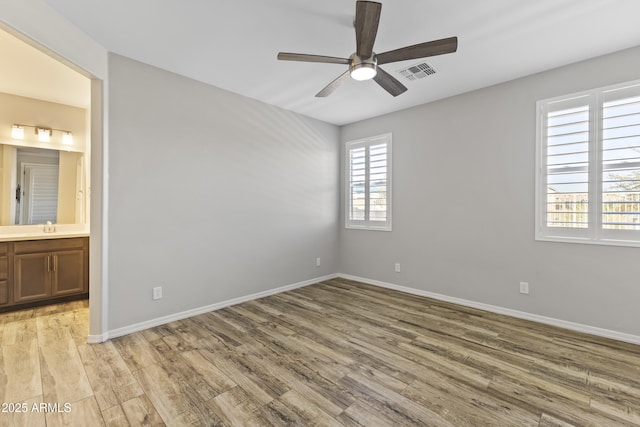 unfurnished room with ceiling fan, sink, and light wood-type flooring